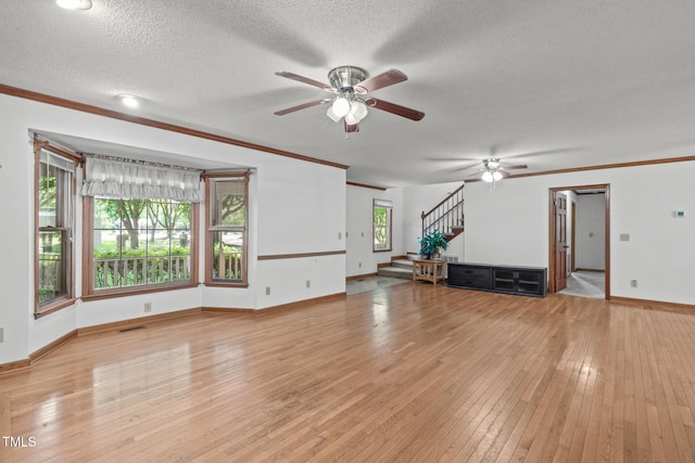 unfurnished living room with baseboards, crown molding, ceiling fan, and stairway