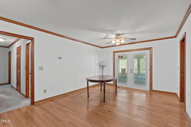 unfurnished dining area with ornamental molding, ceiling fan, a textured ceiling, french doors, and light wood finished floors