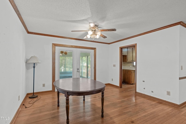 dining room featuring crown molding, ceiling fan, a textured ceiling, french doors, and light wood-style flooring