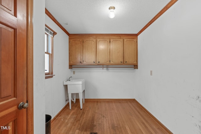 washroom with light wood-style floors, baseboards, ornamental molding, and a textured ceiling