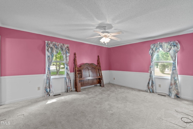 bedroom with crown molding, ceiling fan, a textured ceiling, carpet, and visible vents