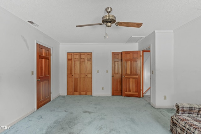 unfurnished bedroom featuring ornamental molding, carpet, a textured ceiling, and visible vents