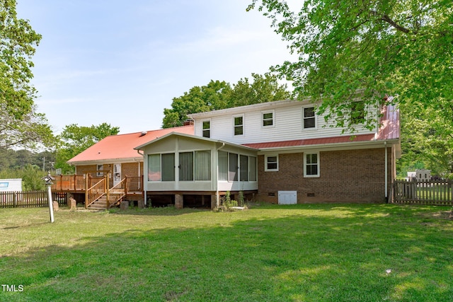 rear view of house featuring a wooden deck, a sunroom, brick siding, fence, and a yard