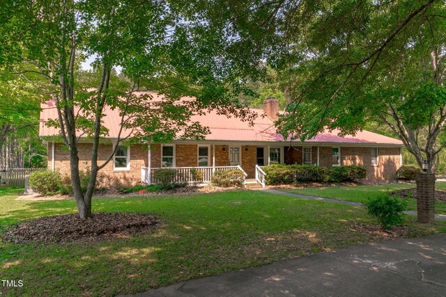 ranch-style house featuring fence, a front lawn, a porch, a chimney, and metal roof
