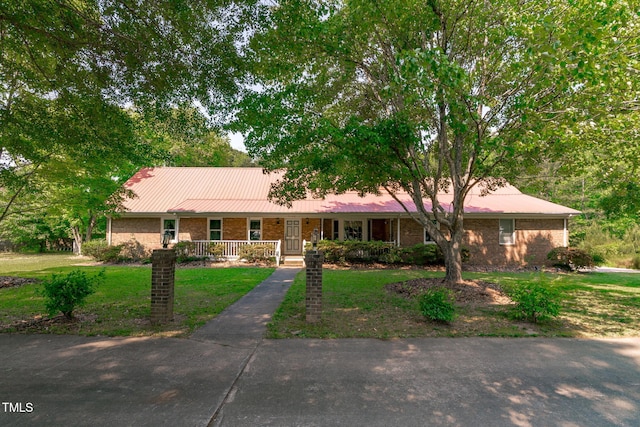 ranch-style home with a porch, brick siding, metal roof, and a front yard