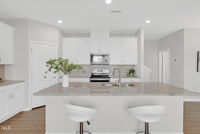 kitchen featuring light wood-type flooring, a sink, appliances with stainless steel finishes, and tasteful backsplash