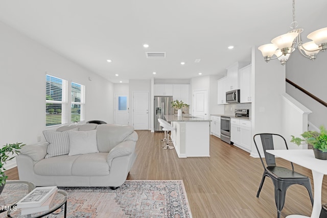living area with visible vents, recessed lighting, light wood finished floors, and a chandelier