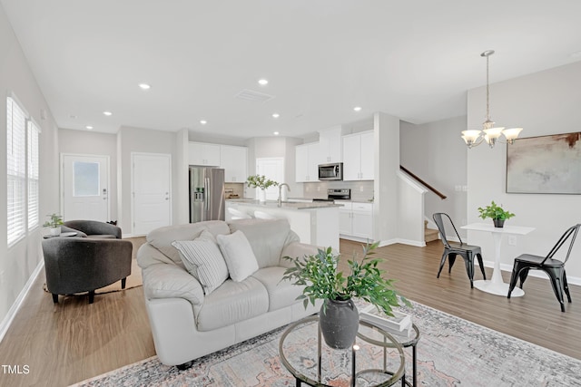 living room featuring a chandelier, recessed lighting, baseboards, light wood-type flooring, and visible vents