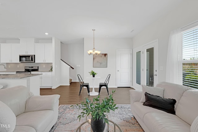 living area featuring dark wood-style flooring, an inviting chandelier, recessed lighting, baseboards, and stairway