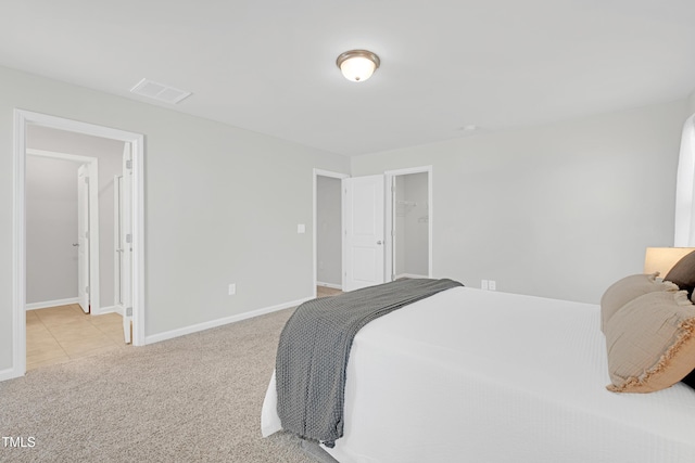 bedroom featuring light carpet, visible vents, baseboards, a spacious closet, and a closet