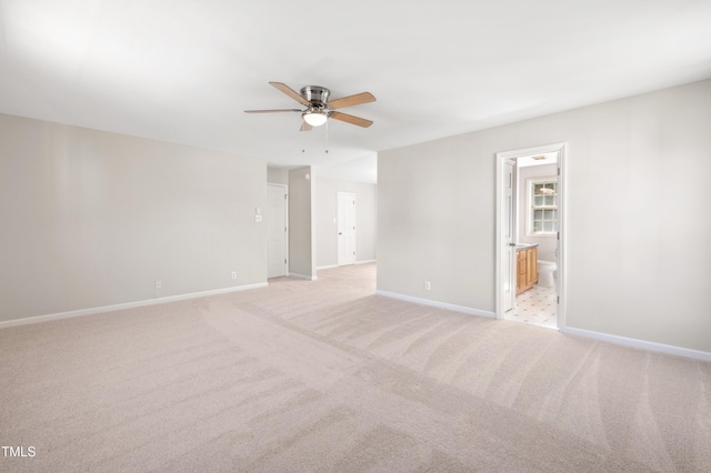 empty room featuring baseboards, a ceiling fan, and light colored carpet