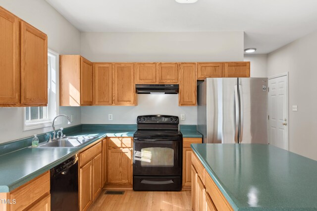 kitchen with visible vents, black appliances, a sink, light wood-style flooring, and exhaust hood