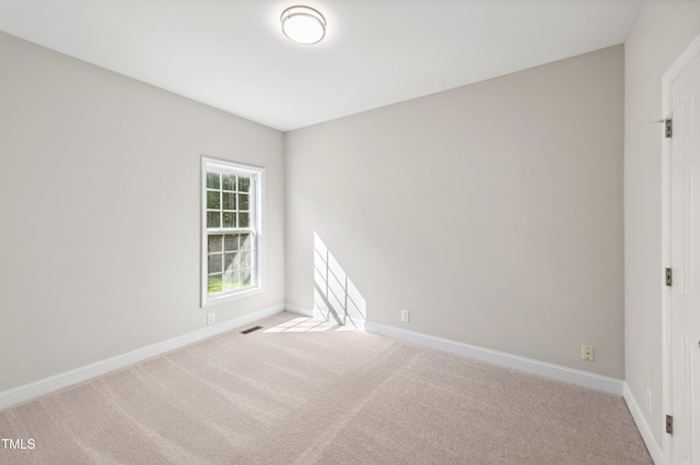 carpeted spare room featuring baseboards and visible vents