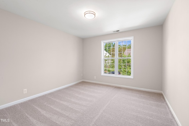 carpeted spare room featuring baseboards and visible vents