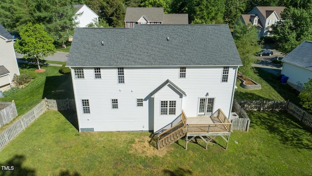 back of house featuring a lawn, a deck, a fenced backyard, and roof with shingles