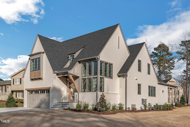 view of home's exterior featuring a garage, brick siding, aphalt driveway, and a shingled roof
