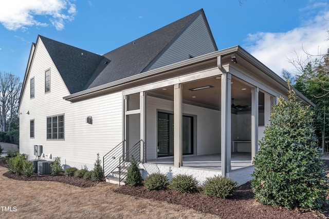 view of home's exterior featuring a ceiling fan, central AC unit, a shingled roof, and a sunroom