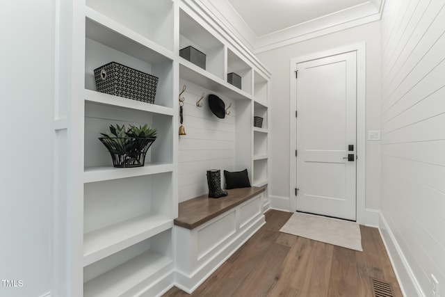 mudroom featuring crown molding, wood walls, visible vents, dark wood-style floors, and built in features