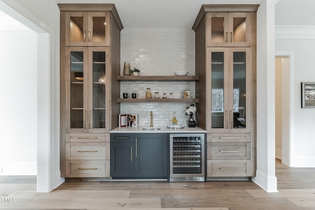 bar featuring baseboards, backsplash, a sink, wet bar, and wine cooler