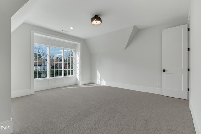 additional living space with visible vents, vaulted ceiling, carpet, and baseboards