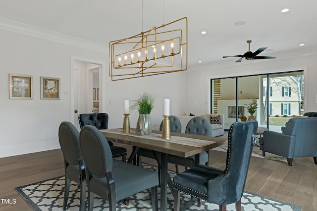 dining space featuring recessed lighting, ornamental molding, ceiling fan with notable chandelier, and wood finished floors