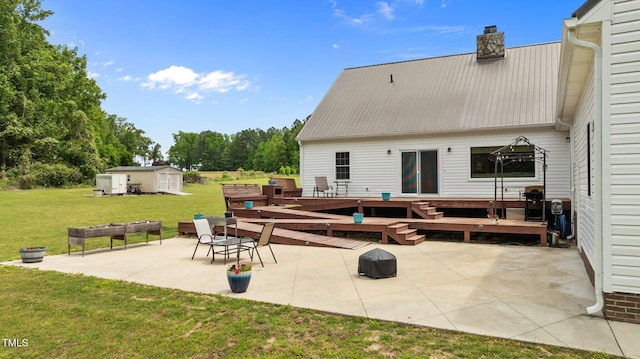 675 Anderson Creek Rd, Henderson, NC 27537 - back of house featuring a yard, a chimney, a patio area, metal roof, and an outbuilding