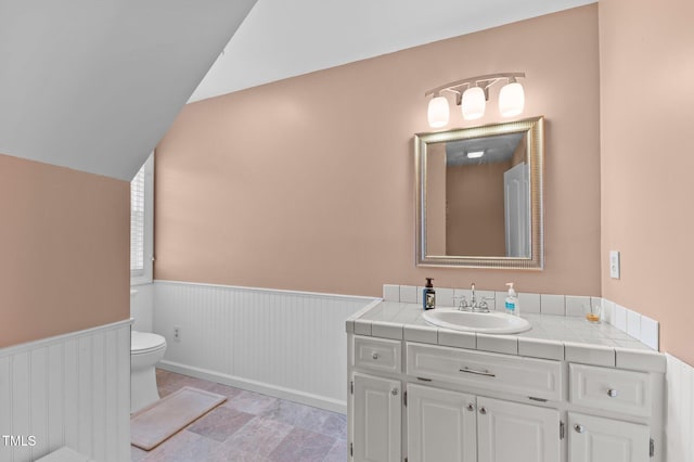 675 Anderson Creek Rd, Henderson, NC 27537 - bathroom featuring vanity, a wainscoted wall, vaulted ceiling, and toilet