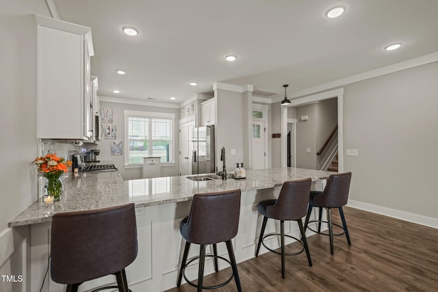 kitchen featuring light stone countertops, range, a sink, white cabinetry, and stainless steel refrigerator with ice dispenser