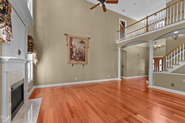 7212 Donneeford Rd, Wake Forest, NC 27587 - unfurnished living room with decorative columns, a ceiling fan, a towering ceiling, a fireplace, and light wood finished floors