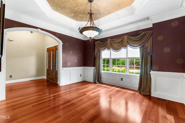 7212 Donneeford Rd, Wake Forest, NC 27587 - unfurnished room featuring arched walkways, ornamental molding, a tray ceiling, wood finished floors, and wainscoting