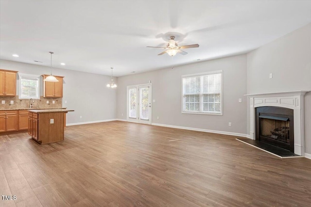 202 Verrazano Pl, Clayton, NC 27520 - unfurnished living room with a ceiling fan, a fireplace with raised hearth, a chandelier, healthy amount of natural light, and recessed lighting