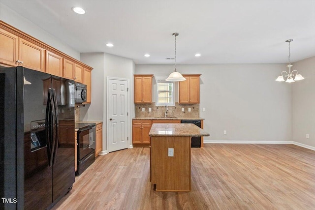 202 Verrazano Pl, Clayton, NC 27520 - kitchen featuring black appliances, light wood-type flooring, decorative backsplash, a kitchen island, and a sink