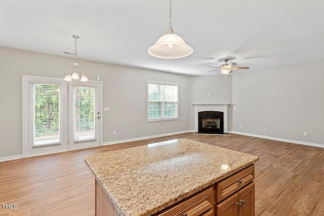 202 Verrazano Pl, Clayton, NC 27520 - kitchen with hanging light fixtures, light wood-type flooring, a ceiling fan, a fireplace, and a chandelier