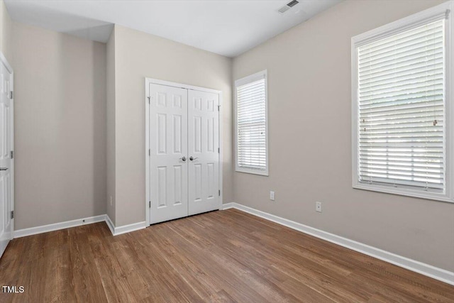 202 Verrazano Pl, Clayton, NC 27520 - unfurnished bedroom featuring wood finished floors, baseboards, a closet, and multiple windows