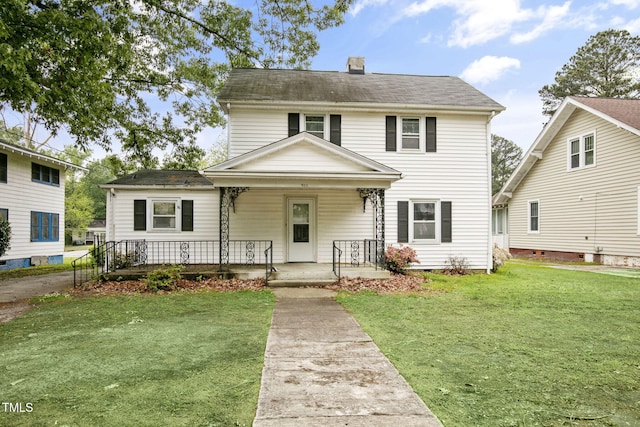 view of front of house with covered porch, a chimney, and a front yard