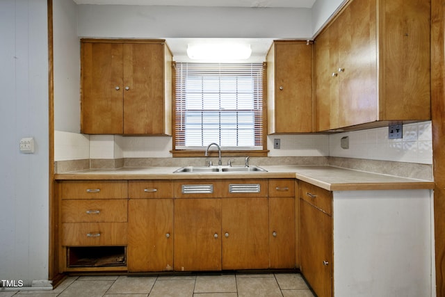 kitchen with light countertops, brown cabinetry, and a sink