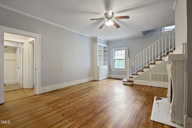 unfurnished living room featuring ceiling fan, hardwood / wood-style flooring, baseboards, ornamental molding, and stairway