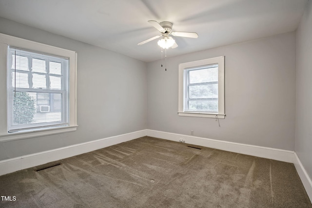 carpeted spare room featuring baseboards, a ceiling fan, and visible vents