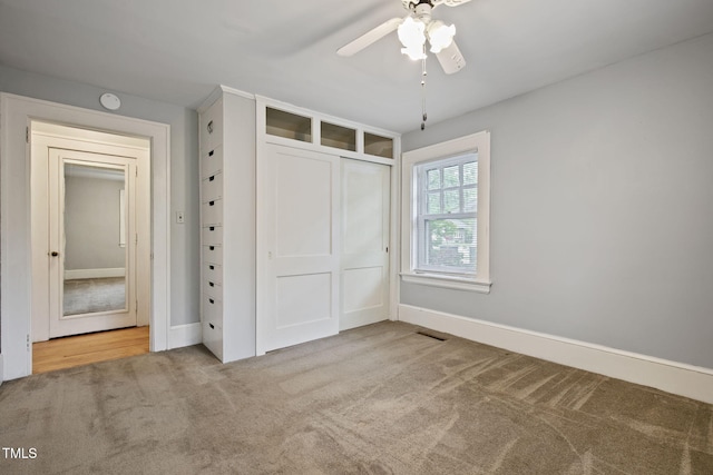 unfurnished bedroom with a closet, carpet flooring, baseboards, and a ceiling fan
