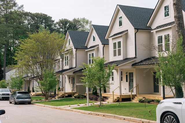 victorian house featuring covered porch, metal roof, a shingled roof, a front lawn, and a standing seam roof