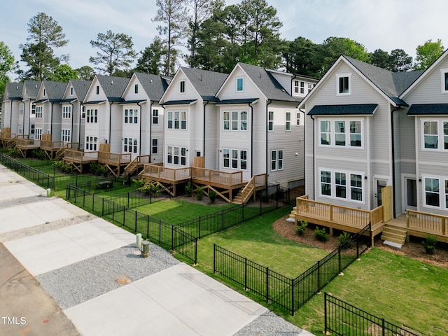 rear view of property featuring a yard, a residential view, a wooden deck, and a fenced backyard