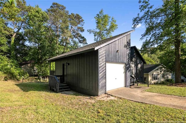 exterior space featuring a lawn, a detached garage, and concrete driveway