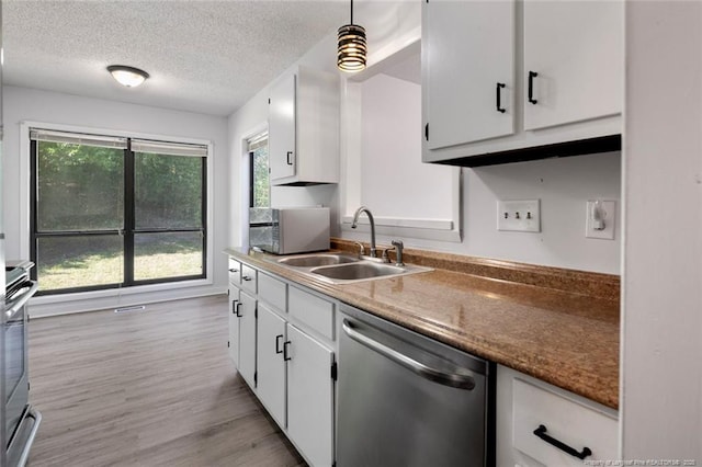 kitchen featuring light wood-style floors, a textured ceiling, white cabinets, a sink, and appliances with stainless steel finishes