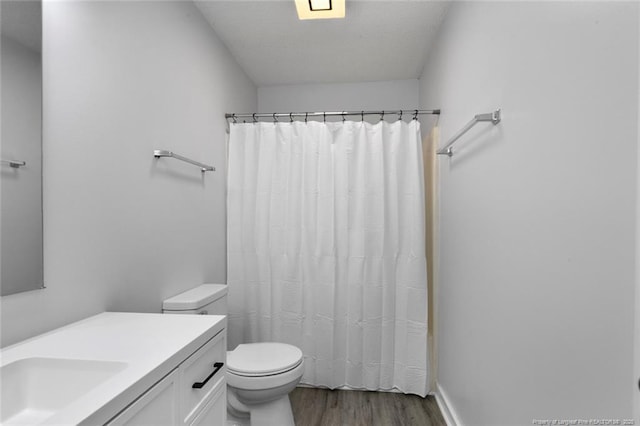 bathroom with vanity, curtained shower, toilet, and wood finished floors