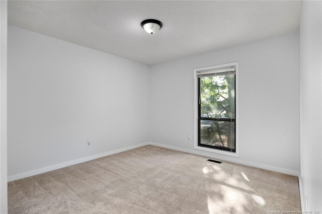 carpeted empty room featuring baseboards and visible vents