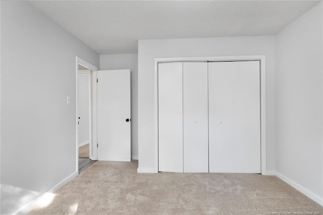 unfurnished bedroom with a closet, carpet, and baseboards
