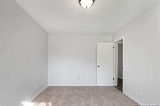 carpeted spare room with baseboards and a textured ceiling
