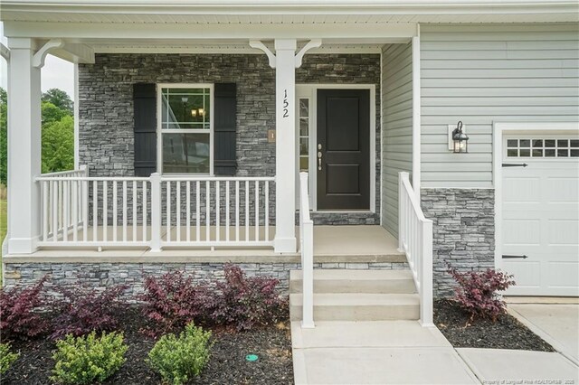 view of exterior entry featuring a porch and stone siding