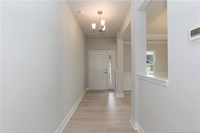 foyer entrance with a chandelier, light wood-type flooring, and baseboards