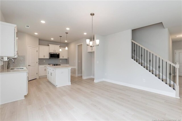 kitchen featuring recessed lighting, light wood-style flooring, stainless steel microwave, a kitchen island, and backsplash